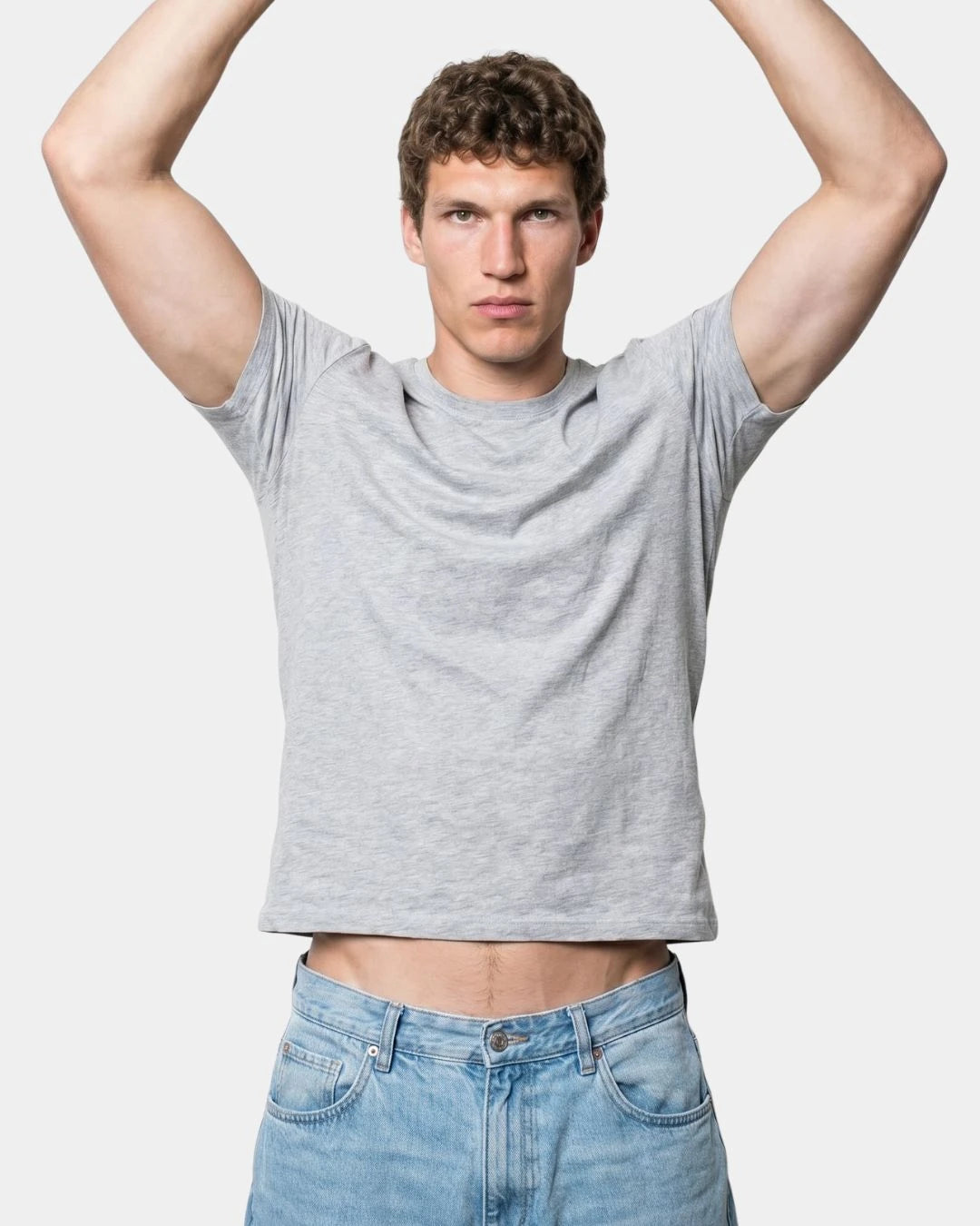 Mann mit erhobenen Armen im Standard-T-Shirt, der Saum rutscht über den Hosenbund