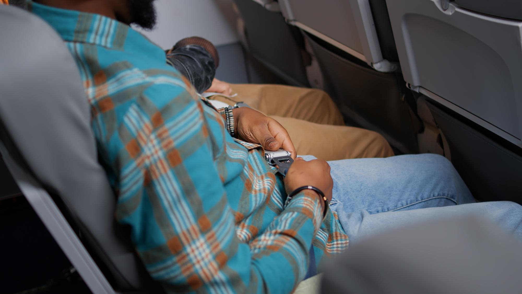 Ein Man sitzt im Flugzeug und hat keine Beinfreiheit
